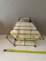 front view showing brass frame, glass panels and shelves