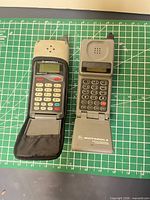 Two open Motorola MicroTAC flip phones side by side on mat