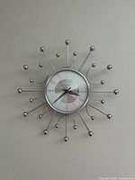 Front view of chrome starburst wall clock showing dial and spokes