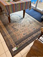 Full view of rug under wooden table with striped tablecloth and sliding door in background