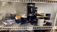 Wide view showing canisters, mugs, small bowls, spoon rest, dip dish, and vintage blue and white tea pot and dishes.