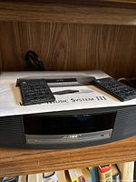 Front view of Bose Wave Music System III with two black remotes and user manual on top