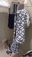 Blue and white patterned drapery panels on hanger with extra items below