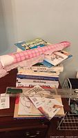Top-down view of stacked art instruction books and sketching tools on a dresser.