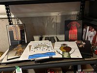 Photos on plaques showing indigenous beaded clothing and accessories, as well as two paintings featuring a fish and an owl, signed 'DF'