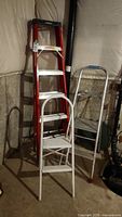 Photo of three ladders in basement: white aluminum paint ladder, white small step stool ladder, red Featherlite 6ft ladder.