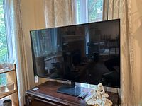 Wide shot of LG 65-inch flat-screen TV on stand with remotes on wooden table