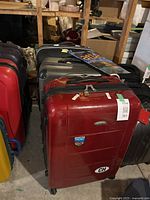 Red Samsonite hard shell suitcase front view with Lausanne and CH stickers, shows signs of usage.