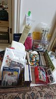 Wide shot of assorted crafting supplies including embroidery kits, floss, fabric, and snap frame on a table.