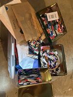 View of the entire bin with multiple tins of embroidery thread and fabric pieces, including needlepoint canvases and embroidery hoops.