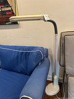 Full view of the off white OttLite floor task lamp next to blue sofa and beige chair.