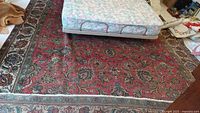 Full view of red Persian rug under mattress showing overall design and wear