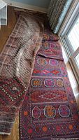 Both runner rugs overlapped with the smaller beige runner folded on top of the red runner.