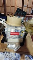 Overall view of the tote filled with various sewing supplies, including measuring tape, thread spools, and a craft book on top.
