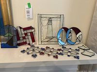 Overall lot display showing 10 stained glass pieces including lighthouse panel, Santas, abstract and small shapes
