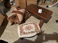 Three stools pictured: A half-round wooden stool, a small needlepoint upholstered stool, and a wood and leather stool.