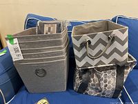 Six grey fabric storage bins, chevron patterned bin, and grey/white tote bag on blue upholstered chair.