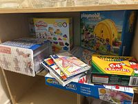 Shelf view showing Play-Doh Shape & Learn Colors & Shapes set, Crayola 64 crayons box, Crayola scented light-up stamper, packs of pencil crayons, Playmobil Summer Fun set and magnetic building blocks container.