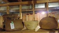 Wicker baskets of assorted sizes placed on a wooden shelf in a basement setting.