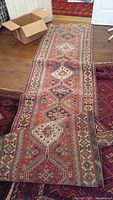 Full-length view of the Persian style runner rug laid out on hardwood floor showing overall pattern and condition