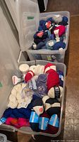 Two plastic totes filled with assorted yarn skeins showing top and bottom tote contents