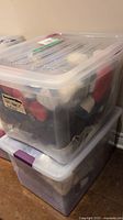 Two clear plastic totes stacked, each filled with yarn skeins