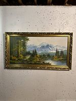 Full front view of the framed oil painting showing the landscape scene with mountains and a lake.