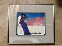 Full view of the framed artwork depicting a stylized figure and adobe buildings with signature visible.