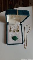 Overview of jewelry set in velvet box showing earrings, pendant with fine chain, loose stone, and separate gold link chain
