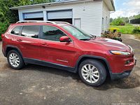 Side view of the red 2017 Jeep Cherokee CA V1 showing overall exterior condition and tinted windows