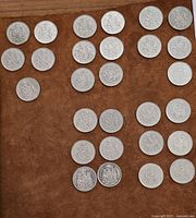 Top down view of 27 Canadian 50 cent coins spread out on brown surface.