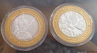 Two tokens side by side showing obverse designs (knight and heraldic creature) with gold outer rings and silver centers