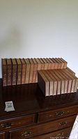 Full set of 28 hardcover volumes of 'The Works of Rudyard Kipling' by Scribners arranged on a wooden dresser.