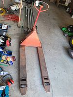 Full pallet jack viewed from above showing the entire tool on a garage floor with some surrounding items.