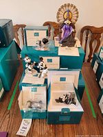 Overview of three teal WDCC boxes with atop displays of villainess on throne, Puppy Love piece, and How to Fly Mickey Mouse.