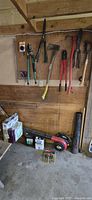 Main overview photo showing pegboard mounted hand tools, leaf blower on floor, boxes and stencils.