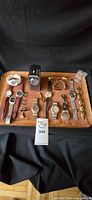Overview of the lot showing watches with leather and metal bands, cufflinks, bracelets, and a wooden box on a tray