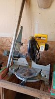 Overall shot of the DeWalt mitre saw including base, saw blade, and adjustable table fence.
