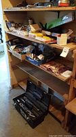 Shelving unit with various boxes and loose plumbing supplies including O-rings, couplings, and tools