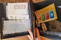Photo of black album page with assorted stamps including Chinese zodiac and floral designs.