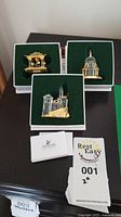 Set of three Swarovski crystal European castle building figurines in green velvet-lined boxes, plus display and literature cards