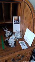 Three crystal animal figurines displayed on mirrored discs with two boxes, certificate pamphlet, and polishing cloth