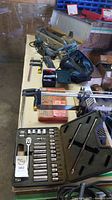 Photo of table with various tools including socket wrench set, clamps and tool bag