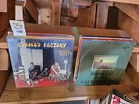 Vinyl record albums stacked including Creedence Clearwater Revival's 'Cosmo's Factory' and Polish album 'Piosenki Jana Galkowskiego'