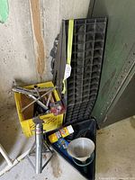 Overall view showing jack stands, ramp stand, oil pan, funnel, spray can and tools in yellow crate