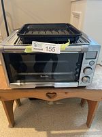Front view of Breville Smart Oven toaster oven with black drip tray placed on top.