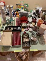 Full view of the candles and candle holders on a table showing boxed red taper candles, votives, tea lights, large pillar candles, and candle holders of glass and metal.