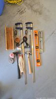Photo showing the entire lot including clamps, levels, miter box, and hammers arranged on the floor.