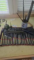 Full view of the 21 piece set arranged on a table including punches, chisels in a roll-up pouch, metal files and rasps in a tin, and two vintage oilers.