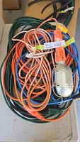 Photo of four coiled extension cords in various colors with one orange trouble light on top